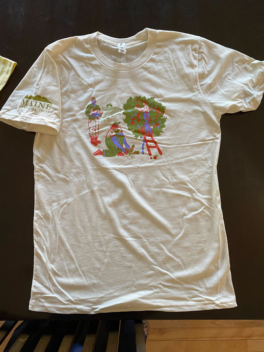 White T-shirt with green, blue and red illustrated graphic showing a farmer holding a chicken, a farmer planting a seedling, and a farmer harvesting apples, with the Maine Farmland Trust logo in olive green on the right sleeve.